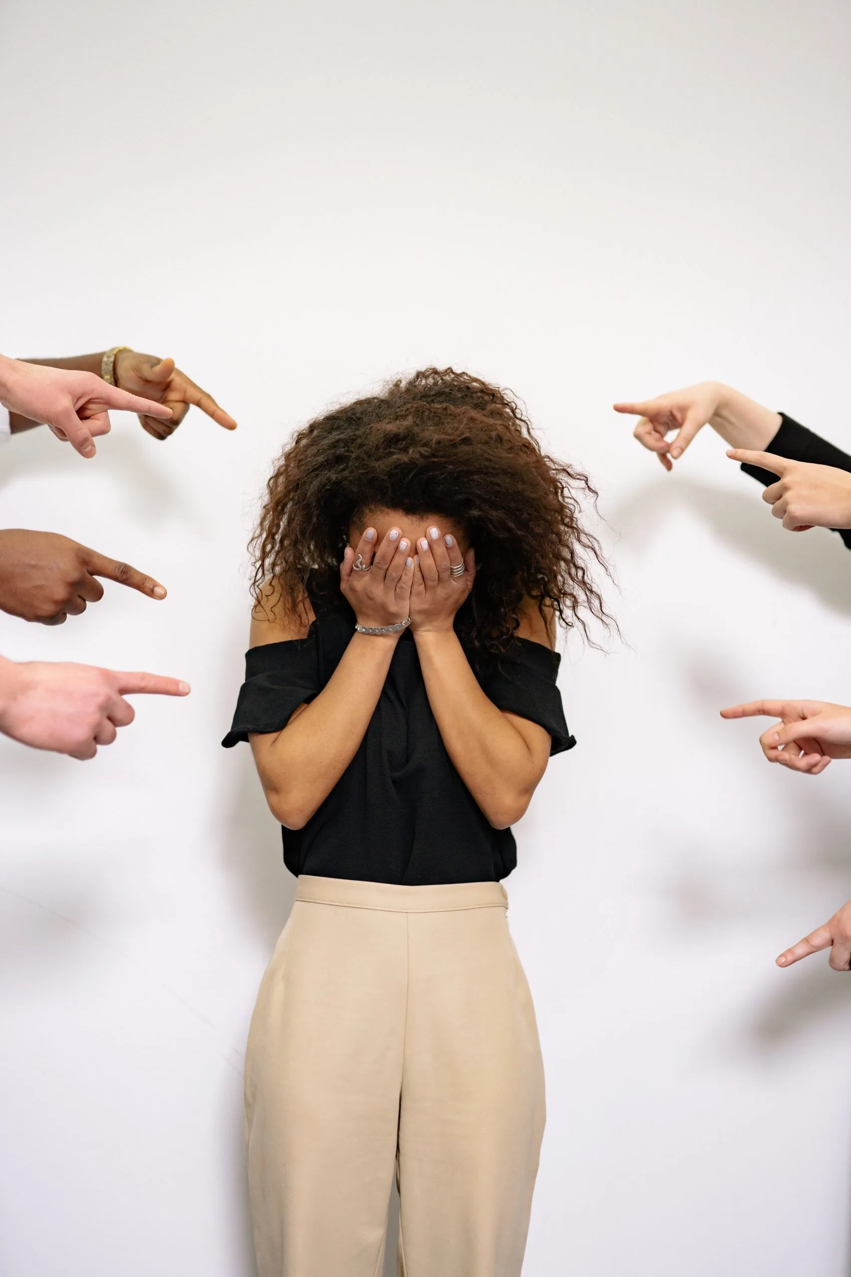 Woman covering her face while colleagues point at her