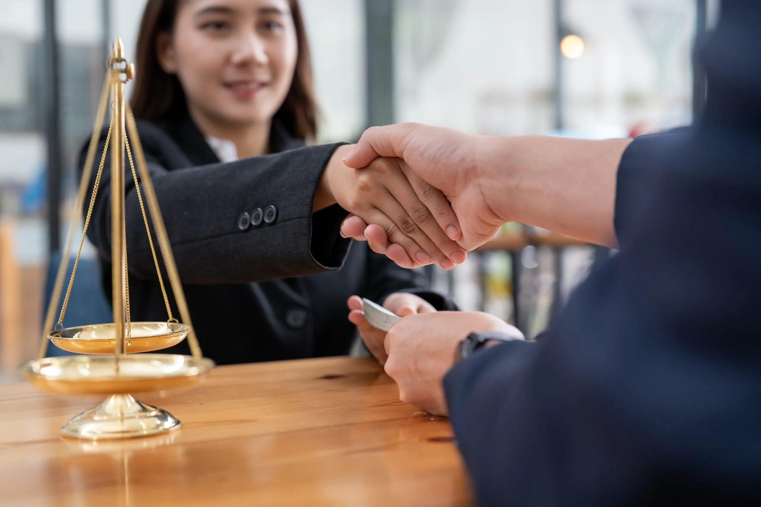 Lawyer shaking hands with a client beside scales of justice
